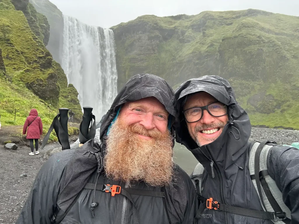 Sean and his hiking companion, Gregg, standing in front of a waterfall in Iceland.