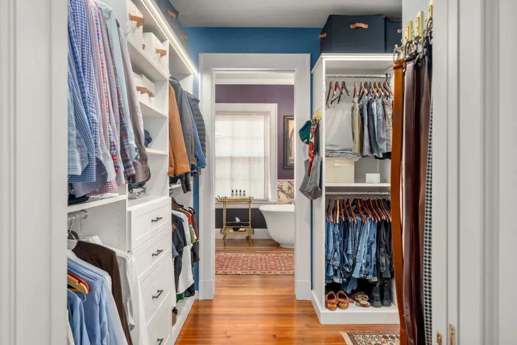walk-in closet remodel with custom shelving and washer dryer, with en suite bath in background