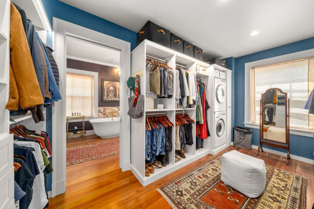 walk-in closet remodel with custom shelving and washer dryer, with en suite bath in background